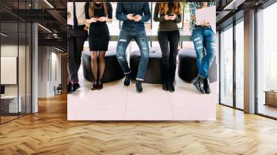 Close up of Group of friends standing on table and browsing in their divices in modern room Wall mural